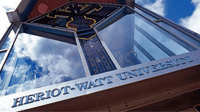 Part-stained glass window above sign that reads 'Heriot-Watt University'